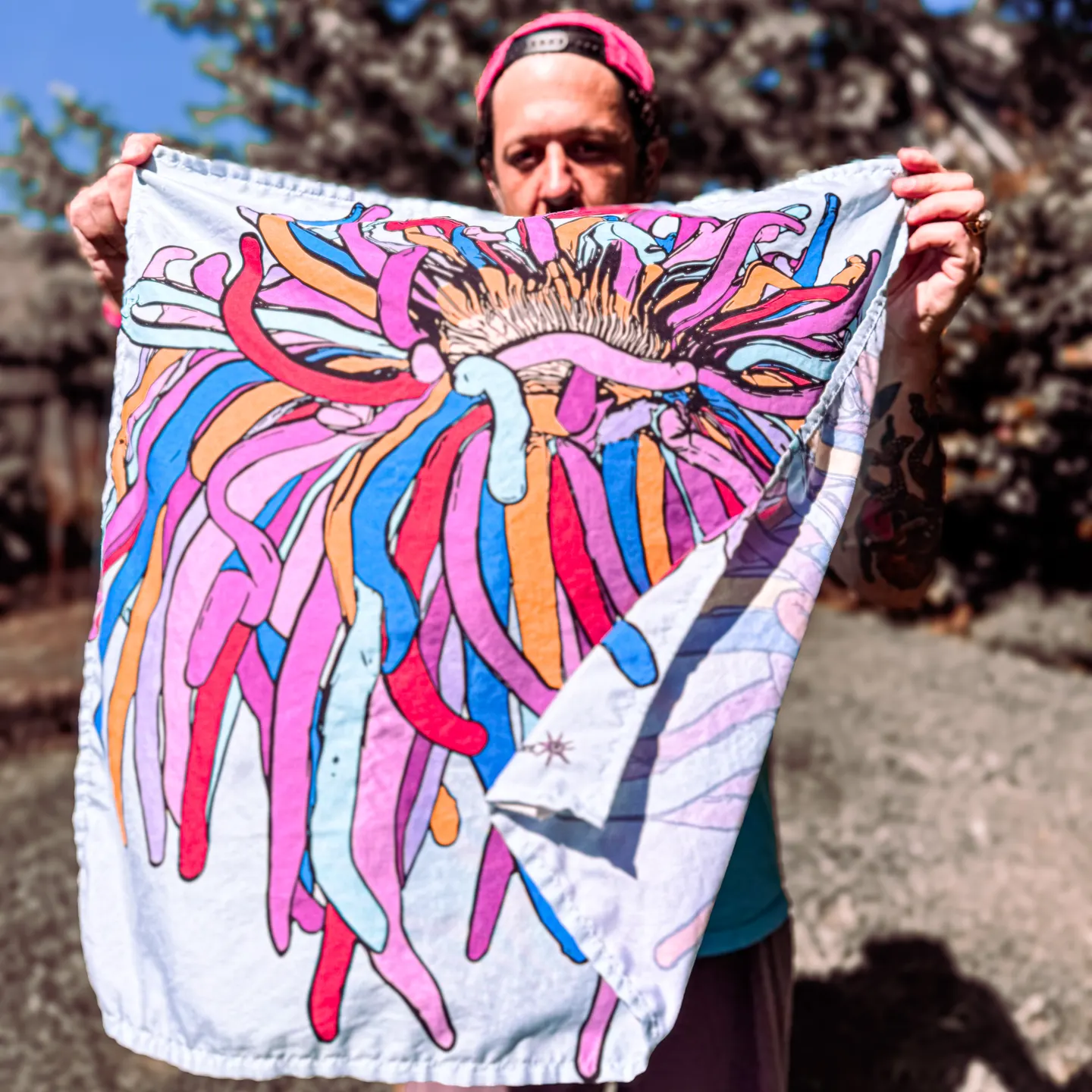 ANEMONE bandana held open in the sun, sea-anemone print in pinks, blues, and oranges — view product